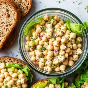 Chickpea salad sandwich filling in a container with bread slices